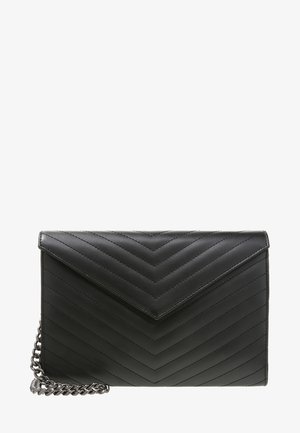 Zwarte leren quilted envelop clutch met chevronpatroon en zilveren kettinkje, geplaatst op een witte achtergrond.