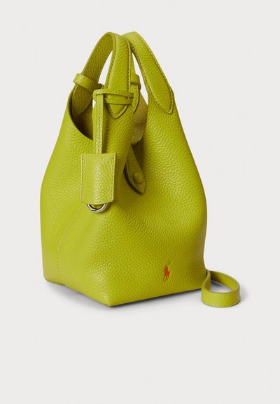 Torba vedra od kože u boji limete sa teksturiranom površinom, bočnom drškom i podesivim remenom. Na prednjoj strani ima mali crveni logo.