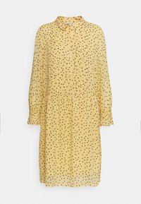 Robe jaune à pois noirs, col de chemise, boutonnage sur le devant, manches longues et taille froncée pour un ajustement décontracté.
