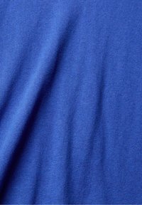 Tissu bleu avec une texture douce et lisse et de légers plis créant des ombres et des reflets doux.