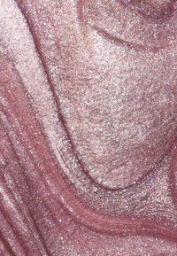 Glitrende pink overflade med en glitrende tekstur, der har svungne mønstre af fine glitrende partikler og en glat finish.