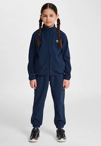 Granatowy dres z polaru składający się z kurtki zapinanej na zamek błyskawiczny oraz spodni z elastycznym pasem, uzupełniony o niewielkie logo na kurtce.