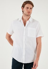 Witte kortekousen knoopshirt met een gestructureerde stof, een borstzak en een klassieke kraag. Gecombineerd met donker denim jeans.
