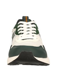 Sneakers med en vit tygöverdela och gröna mockadetaljer, en svart gummisula och vita snören; orange "ENDURANCE"-etikett vid hälen.