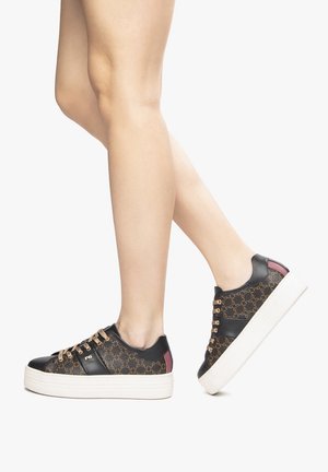 Sneaker neri e marroni a fantasia con suola bianca chunky, dotate di lacci dorati e un accento bordeaux sul tallone. Design piatto, tomaia in tessuto.