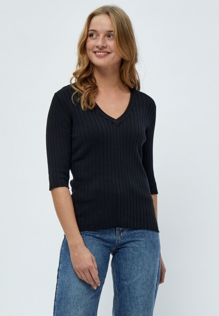 Schwarzes, geripptes Strickoberteil mit V-Ausschnitt und Dreiviertelärmeln, das eine figurbetonte Passform und eine weiche Textur aufweist. Kombiniert mit blauen Jeans.