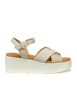 Sandali platform beige con accento intrecciato, cinturini in suede, fibbia regolabile alla caviglia e una spessa suola bianca. Texture liscia.