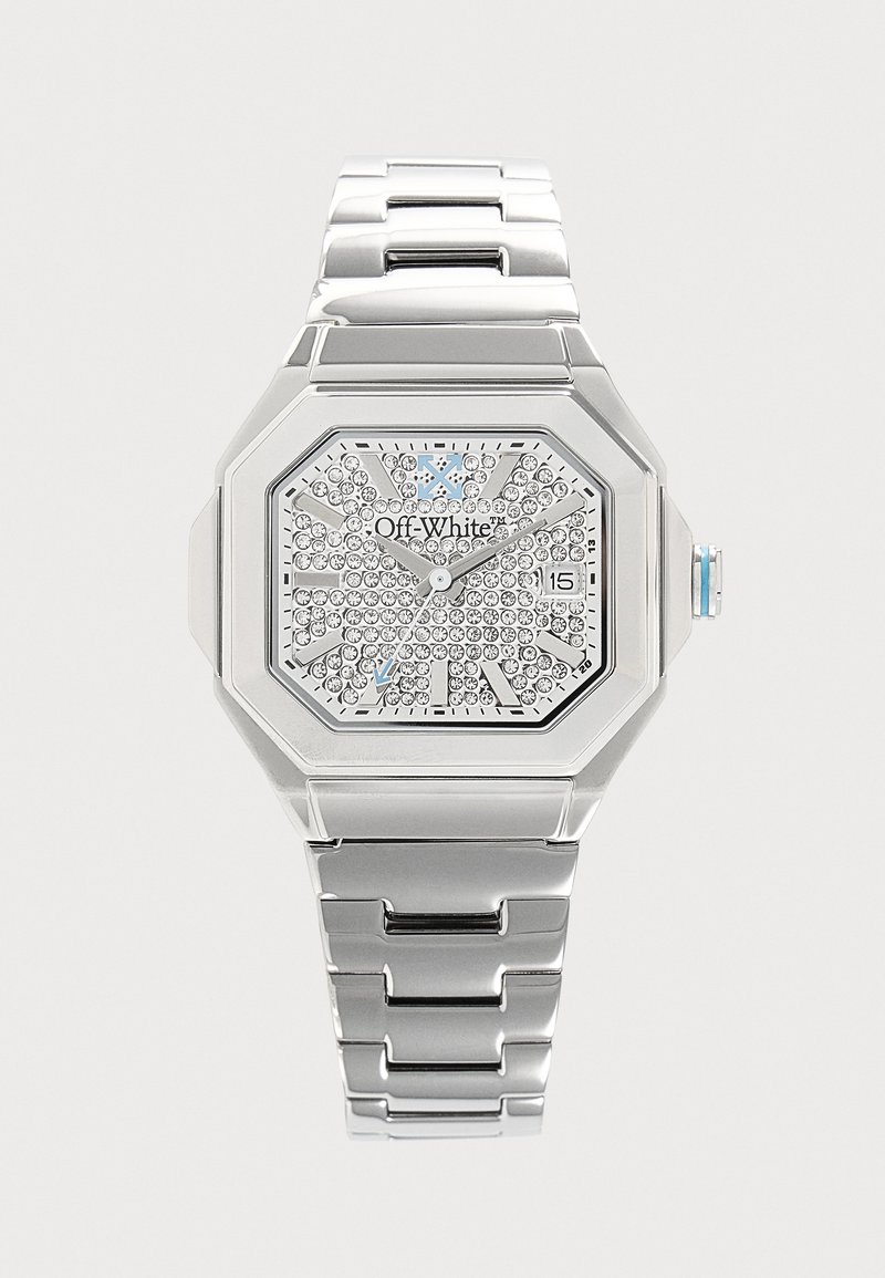 Montre-bracelet en métal argenté avec un cadran octogonal, un cadran orné de cristaux, un affichage de la date et un logo "Off-White" sur le cadran.