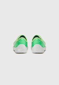 Gröna slip-on skor med en texturerad överdel, i en ljusgrön nyans, vita gummisulor och en subtil "superfit"-logotyp på hälen.