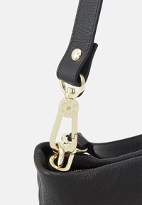 Anse de sac à main en cuir texturé noir avec fermoir et attache anneau dorés, montrant des coutures détaillées et une quincaillerie de marque.