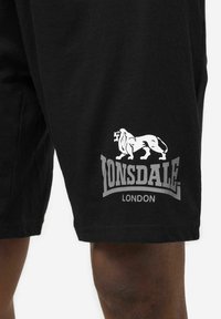 Czarne bawełniane spodenki z białym logo lwa i szarym napisem "LONSDALE LONDON". Standardowy krój, gładka faktura, długość do kolan.