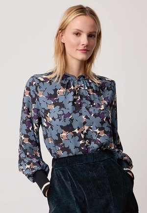 Long-sleeve blouse in dark fabric with a floral pattern. Features a gathered neckline and elastic wrist cuffs. Color palette includes blue and mauve.
