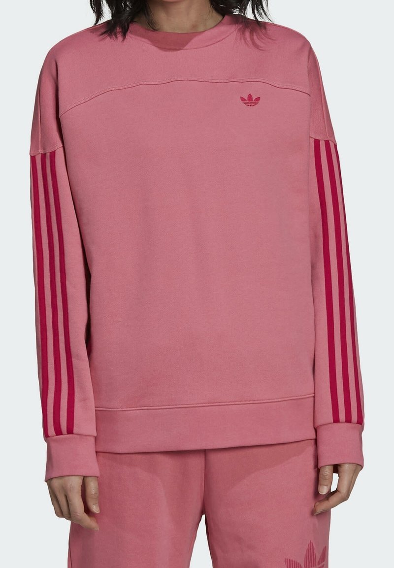 Rosa sweatshirt av mjukt tyg, med rund halsringning, långa ärmar och röda vertikala ränder på ärmarna. Liten logotyp på bröstet.