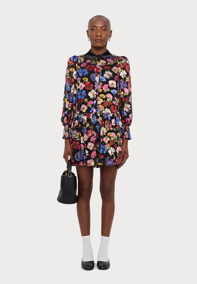 Blomsterkjole med sort bund, lange ærmer og krave. Har farverige blomsterdesigns og et lagdelt look. Matchet med en sort taske.
