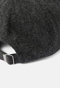 Gorra de lana gris oscuro con una superficie texturizada. Presenta una correa ajustable de metal plateado en la parte posterior, marcada con "GANT."