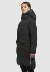 Schwarze Daunenjacke mit hohem Kragen und Kapuze, ausgestattet mit einem Reißverschluss auf der Vorderseite, Seitentaschen und einer eleganten, gesteppten Textur.