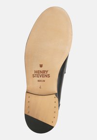 Suola di scarpa in pelle con una finitura beige liscia, caratterizzata da un accento nero, con il nome del marchio inciso "HENRY STEVENS BERLIN" e cinque piccoli chiodi metallici.