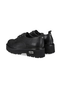 Scarpe in pelle nera con punta rotonda, suola a piattaforma rialzata e texture spessa a coste. Presentano lacci e dettagli del logo sul lato.