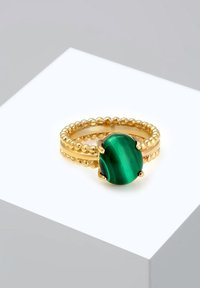 Bague en or avec un bandeau texturé et un centre en malachite verte, présentant une surface lisse et une forme ovale. Taille 925 gravée à l'intérieur.