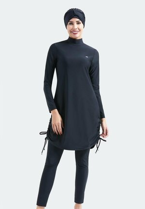 Schwarze Schwimmtunika mit langen Ärmeln, seitlichen Kordelzügen, hohem Kragen und passenden Leggings. Hergestellt aus dehnbarem, leichtem Stoff.