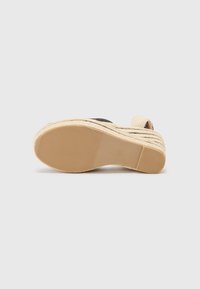 Sandale espadrille noire avec une sangle tissée, dotée d'une semelle en jute naturel et d'une semelle extérieure en caoutchouc texturé pour une adhérence optimale.