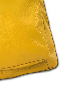 Sacoche en cuir jaune à la texture douce, présentant une forme arrondie et sans matériel ou motifs visibles. Fini lisse.