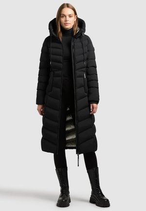 Black puffer coat with a hood, featuring a long design, quilted texture, and a contrasting light lining. Accompanied by black combat boots.