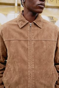 Barna szarvasbőr dzseki cipzáras elülső résszel, strukturált gallérral és két oldalzsebbel. Sima textúrájú, díszítés nélküli kialakítás.