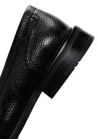 Botín negro de cuero hasta el tobillo con una superficie texturizada, tacón de madera negra plano y sutiles costuras a lo largo del costado.