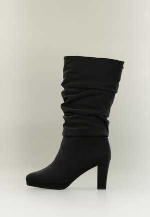 Black mid-calf slouchy boot with rounded toe and chunky high heel on a plain light background.