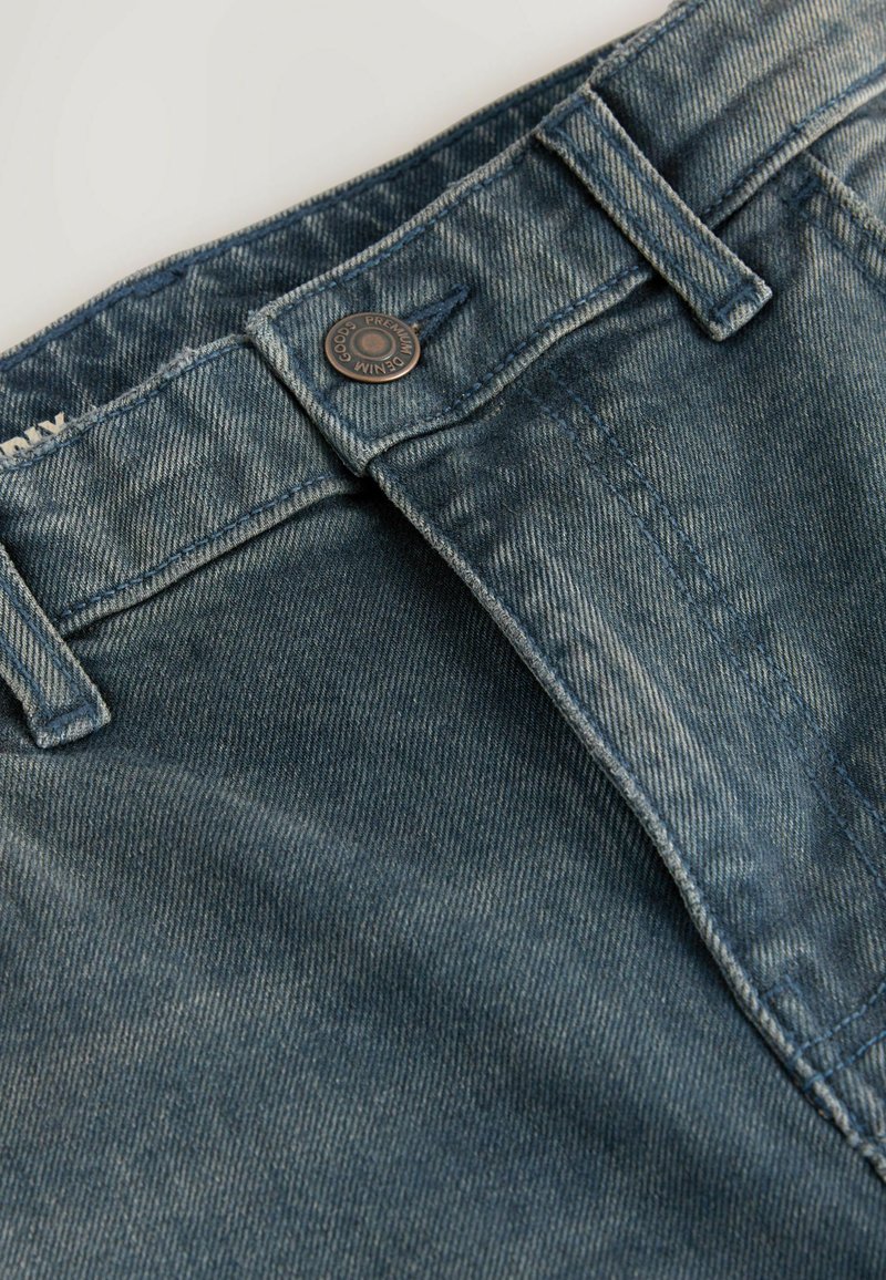Denim-Jeans in einem verblassten blauen Waschgang, ausgestattet mit einem Metallknopfverschluss, klassischen Taschen und kontrastierenden Nähten entlang der Säume.