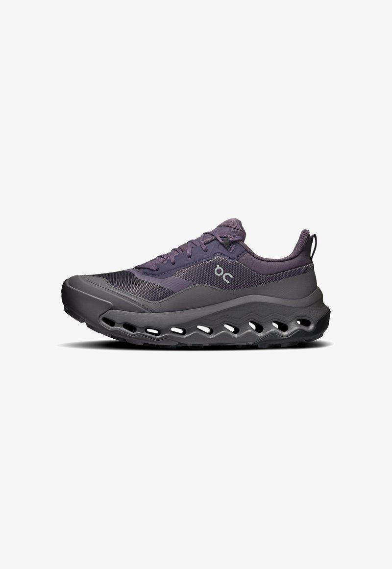 Baskets de sport violet foncé et noir avec dessus en mesh, lacets à l'avant et semelle épaisse avec découpes ovales.