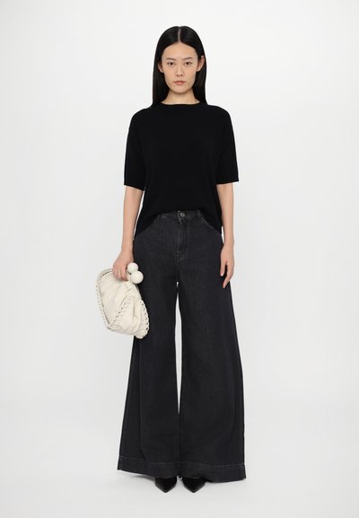 Black short-sleeve top, wide-leg dark denim jeans, and a cream handbag with a braided accent. Simple design with a relaxed fit.
