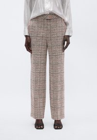 Woven wide-leg trousers in textured beige with orange and black accents, featuring a button closure and two side pockets.