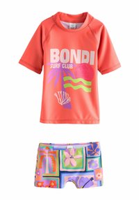 Valkokorallinen rash guard, jossa on teksti "BOND| SURF CLUB" ja trooppisia grafiikoita. Samanlaiset uima-shortsit, joissa on värikkäitä kukka- ja geometrisia kuvioita.