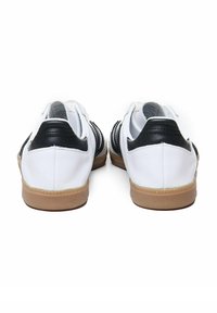 Baskets en cuir blanc et noir avec des accents texturés, semelles en caoutchouc et talons arrondis, vues de l'arrière.