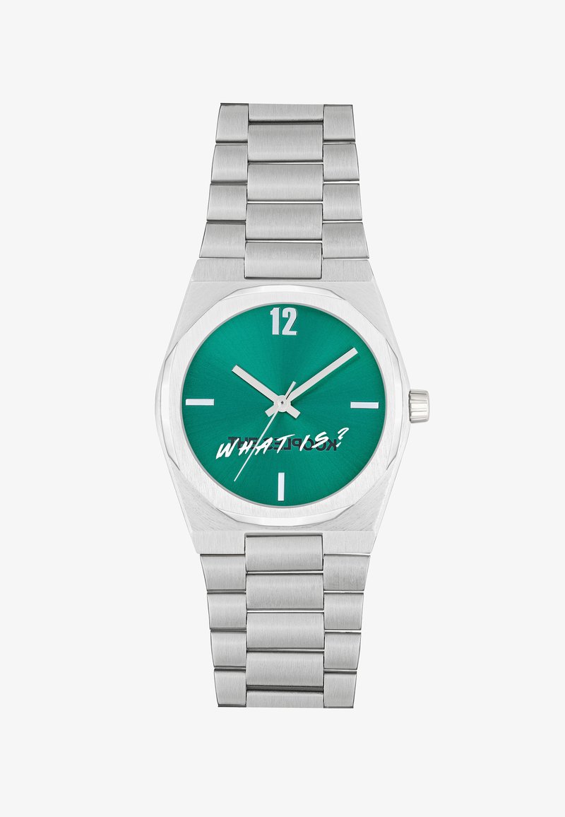 Sidabrinis nerūdijančio plieno laikrodis su žalia ciferblatu, aštuonkampiu korpusu ir drąsiais baltais žymėjimais. Visoje struktūroje yra šlifuotas metalinis dirželis ir užrašas "KAS YRA?"