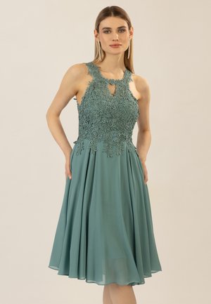 A teal dress with a floral lace bodice, keyhole neckline, and A-line skirt. Smooth texture and knee-length, with shoulder cutouts.