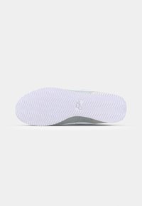 Shoe sole featuring a white rubber base with a zigzag tread pattern, and a smooth grey upper section, stitched at the edge.