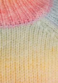 Tissu tricoté dans des tons pastel de rose, vert et jaune. Présente des points texturés et une transition de couleur dégradée du haut vers le bas.