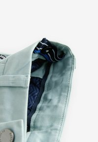 Light green fabric with a smooth texture, featuring a dark blue patterned interior and striped hardware accents at the opening.