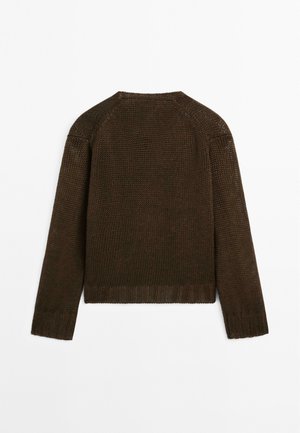 Brun stickad tröja med strukturerad yta och ribbad fåll, med långa ärmar och rund halsringning. Baksidan är enkel utan dekorationer.