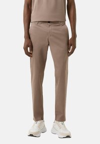 Lysebrune chinos lavet af bomuldsblandingsstof, med en slank pasform, standardlommer og en glat tekstur, parret med hvide sneakers.