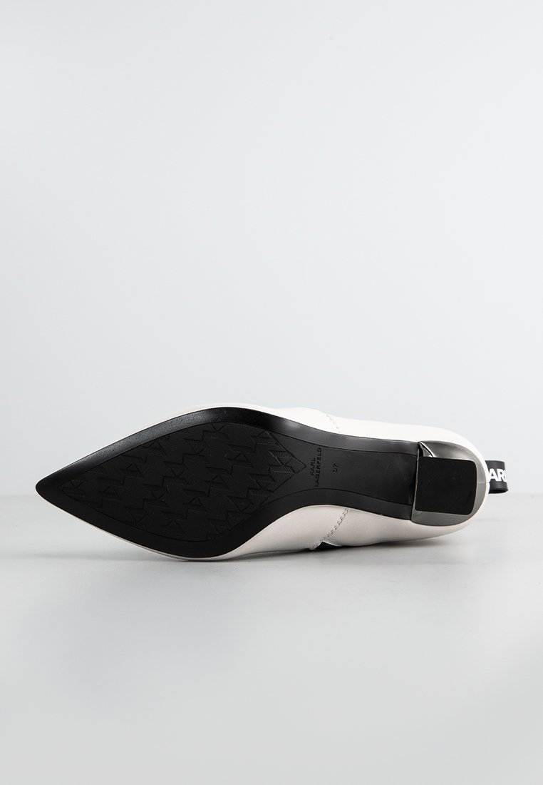 Weiße High-Heels mit spitzem Zehenbereich, die ein elegantes Design aufweisen und eine schwarze, strukturierte Gummisohle haben, mit einem silbernen Akzent am Absatz.