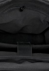 Svart tygpåse inuti med mjuk textur, utrustad med en horisontell dragkedja och ett vertikalt band för säker stängning.