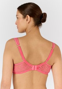 Sostén de encaje rosa con tirantes ajustables y cierre de gancho. Presenta un patrón floral y una banda de textura suave. Diseñado para brindar soporte.