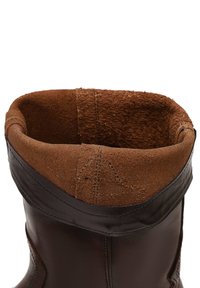 Vista superior de una bota de cuero marrón con un forro interior suave, similar al ante, y costuras visibles alrededor del puño.