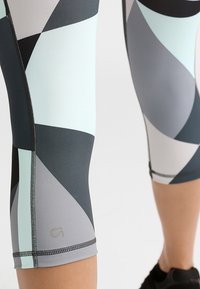 Legginsy kompresyjne z geometrycznym wzorem w kolorze miętowym, szarym i czarnym, z płaskimi szwami i gładkim, elastycznym materiałem.