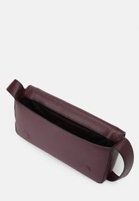 Burgundyröd läderväska med en slät yta, rektangulär form, enkel rem och en öppen topp som avslöjar ett svart inre samt en organiseringsficka.