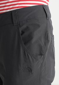 Svarta utomhusshorts med en mjuk yta, utrustade med en sidoficka och en broderad logotyp av "The North Face" nära fållen.